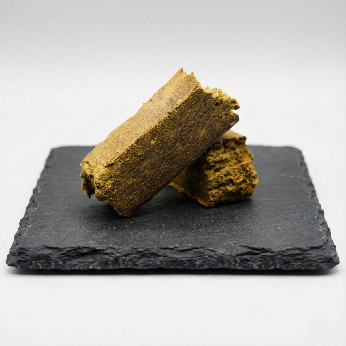 Dry Hash GR33NZ : hashish CBD bio artisanal sur ardoise. Texture claire et friable, issu de pollen pressé à sec. Pur, naturel et sans solvants.