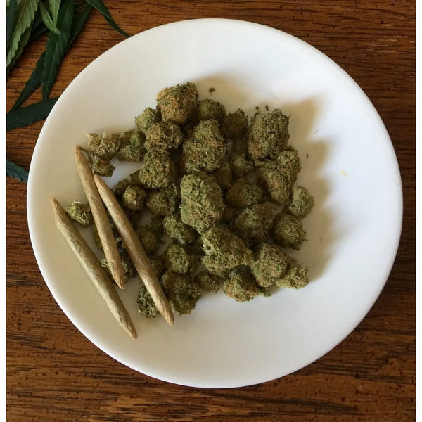 fleurs de CBD et des joints pré-roulés, posés sur une assiette blanche