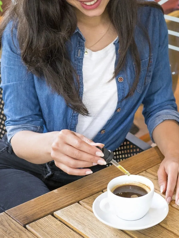 femme ajoutant quelques gouttes d'huile de CBD à son café