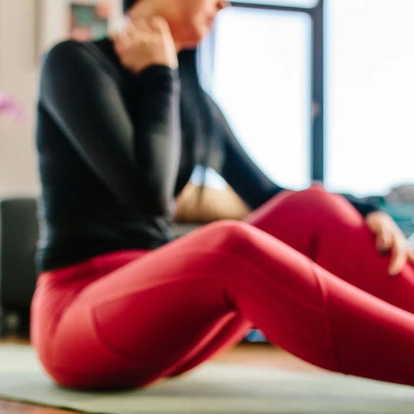 Femme en tenue de sport se massant la nuque après l'entraînement, illustrant l'utilisation du baume CBD Gr33nz pour soulager les tensions et courbatures musculaires.