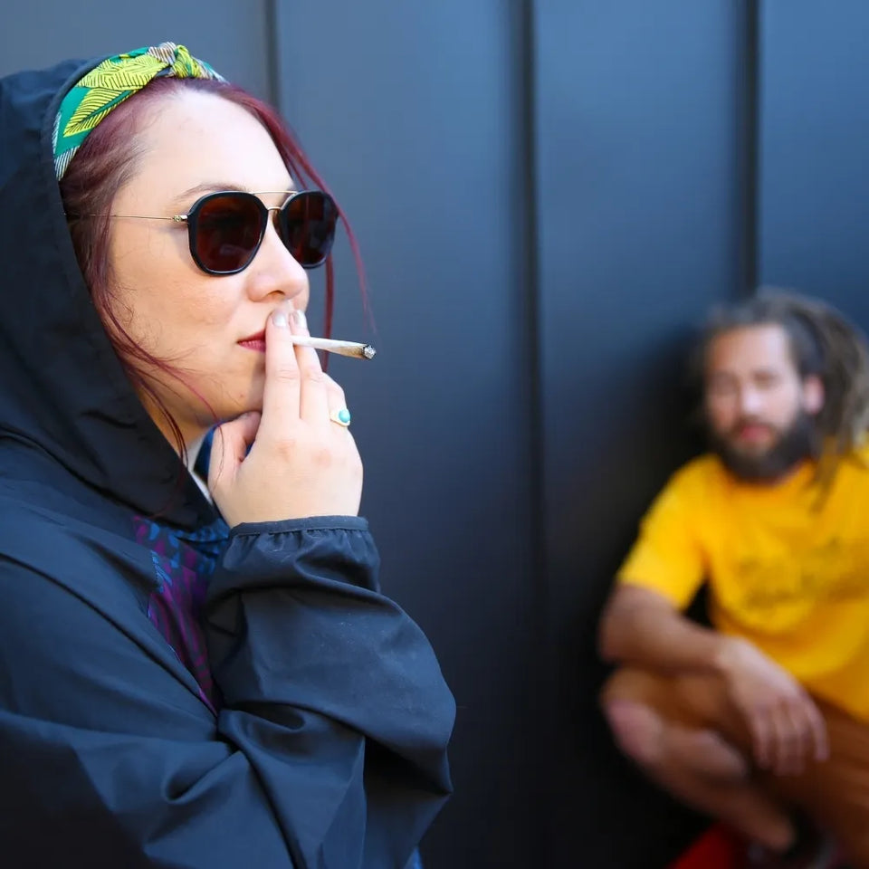 Femme décontractée fumant un joint de CBD, avec un homme en arrière-plan – GR33NZ