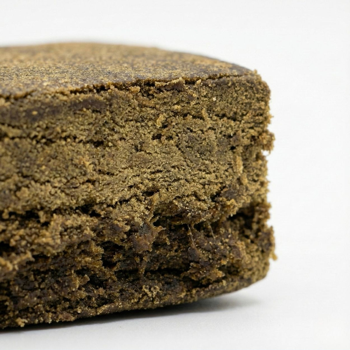 Vue macro du Surver Hash GR33NZ : résine CBD bio compacte et granuleuse, issue de pollen tamisé pressé à froid. Texture riche et arômes authentiques.