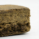 Vue macro du Surver Hash GR33NZ : résine CBD bio compacte et granuleuse, issue de pollen tamisé pressé à froid. Texture riche et arômes authentiques.