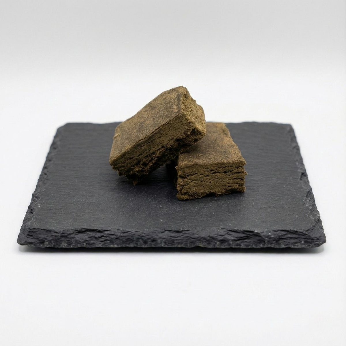 Surver Hash GR33NZ présenté sur ardoise : résine CBD bio issue de pollen tamisé et pressé à froid. Texture naturelle, pureté artisanale et taux de THC < 0,3 %.