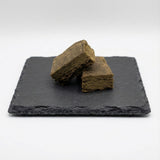 Surver Hash GR33NZ présenté sur ardoise : résine CBD bio issue de pollen tamisé et pressé à froid. Texture naturelle, pureté artisanale et taux de THC < 0,3 %.