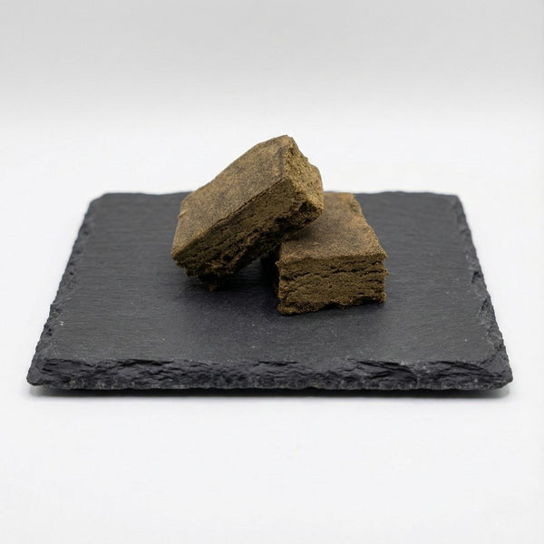 Surver Hash GR33NZ présenté sur ardoise : résine CBD bio issue de pollen tamisé et pressé à froid. Texture naturelle, pureté artisanale et taux de THC < 0,3 %.