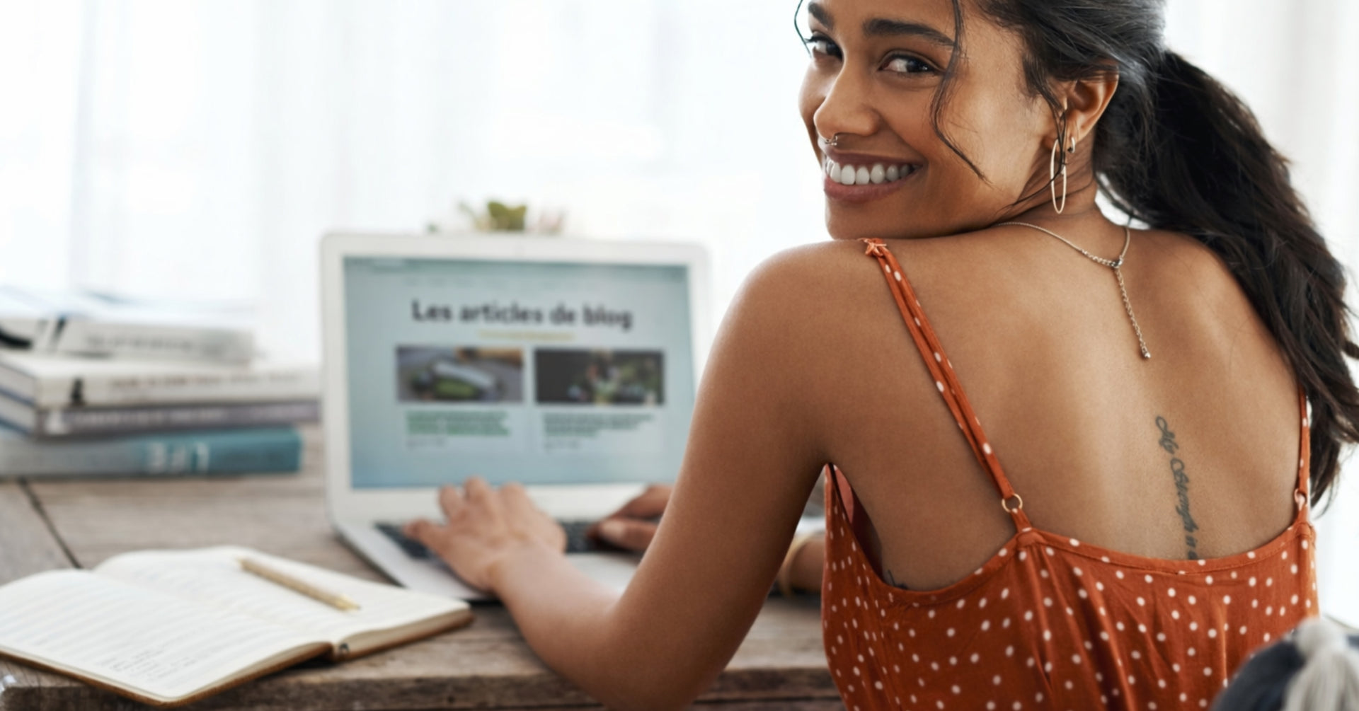 Portrait d'une jeune femme souriante travaillant sur son ordinateur portable, illustrant la consultation d'articles de blog et de conseils bien-être sur le site GR33NZ.
