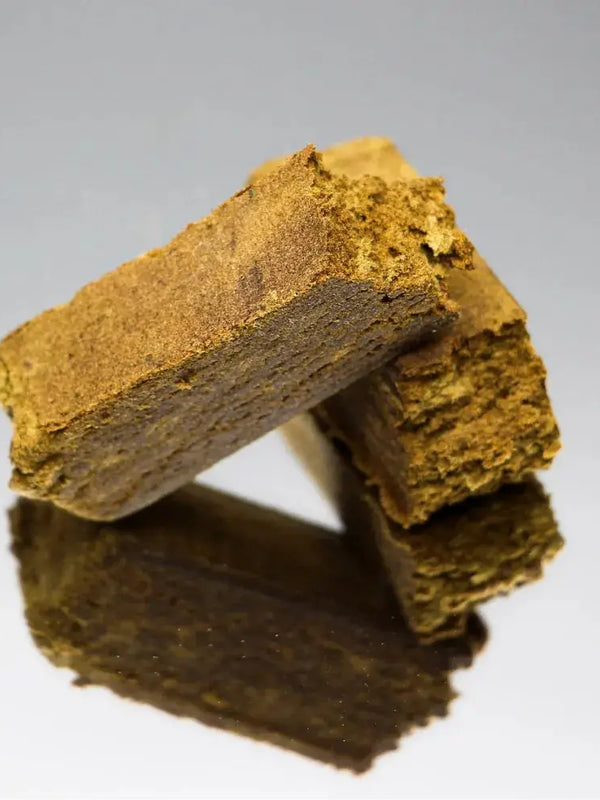 Gros plan sur la résine de CBD Dry Hash Bio de Gr33nz, un extrait naturel issu du pollen de fleurs de CBD, tamisé et pressé à froid, garantissant une concentration optimale en cannabinoïdes.