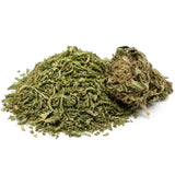 Trim CBD Harlequin avec sa fleur CBD sur fond blanc, montrant un tas de trim vert finement broyé accompagné d’une tête de fleur riche en trichomes.